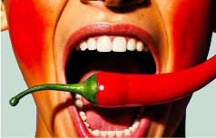 close up of a woman with her mouth open and a about to bite on a red chilli