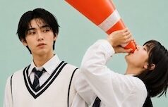 a woman holding up a traffic cone to her mouth and a man looking at her